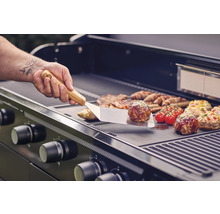 Gasgrill mit Grillgut und Grillbesteck im Einsatz