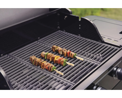 Trois brochettes de viande sur une grille de barbecue.