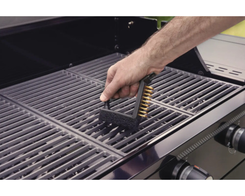 Eine Person reinigt einen Grillrost mit einer Grillbürste.