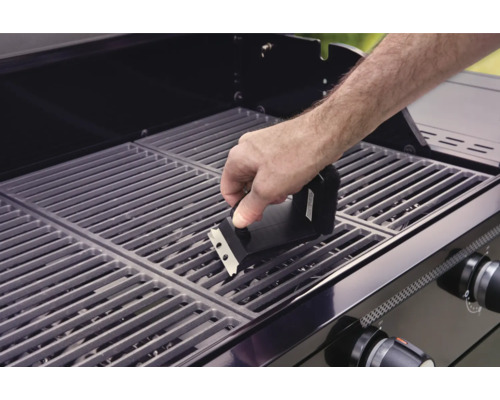 Eine Person reinigt mit einer Grillbürste einen Grillrost.