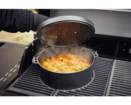 Schmortopf mit Deckel auf einem Grill mit Speisen darin