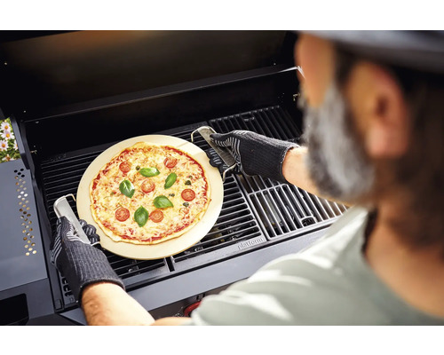 Une pizza sur une pierre à pizza est préparée avec un gril dans un barbecue.