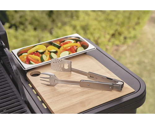 Légumes dans un plat, pince de barbecue et planche à découper sur un barbecue