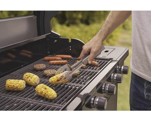 Barbecue avec des aliments grillés tels que des épis de maïs, des saucisses et des galettes de hamburger, une personne utilise une pince à barbecue.