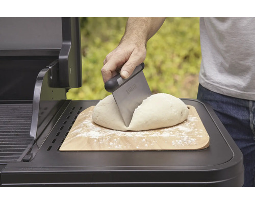 Teig auf Holzbrett wird mit Teigschaber auf Grill geteilt