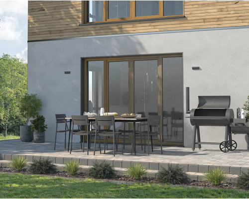 Terrasse avec table de jardin, chaises et barbecue devant une maison