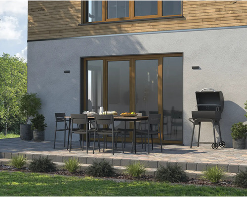 Aussenszene mit Grill, Gartentisch und Stühlen auf einer Terrasse vor einem Wohnhaus