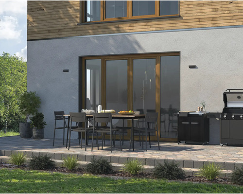 Espace extérieur avec table de jardin, chaises et barbecue sur une terrasse à côté d''une maison.