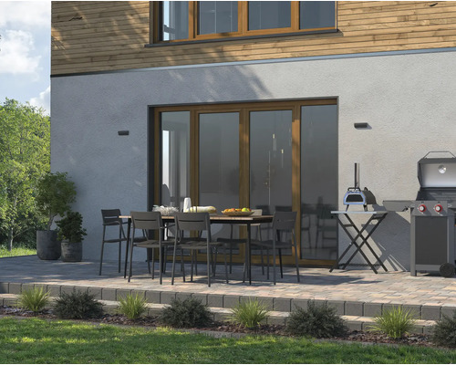 Terrasse avec table à manger, chaises, barbecue et four à pizza devant une maison