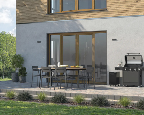 Terrasse avec barbecue à gaz, table de jardin et chaises devant une maison