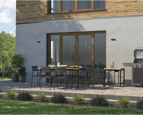 Terrasse mit Esstisch, Stühlen, Grill und Grillwagen vor einem Haus