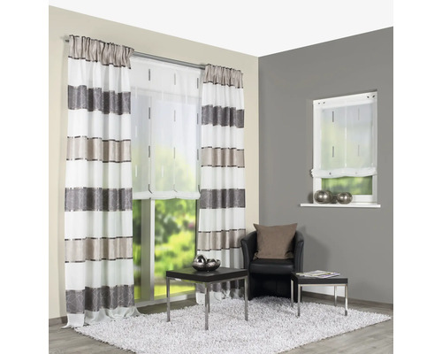 Raumansicht mit gestreiften Vorhängen, Rollo und Sessel auf einem Teppich