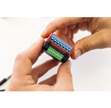 Hände halten ein elektronisches Bauteil mit Anschlussklemmen