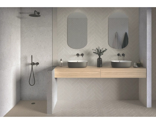 Salle de bains lumineuse avec douche, double vasque et carrelage à chevrons.