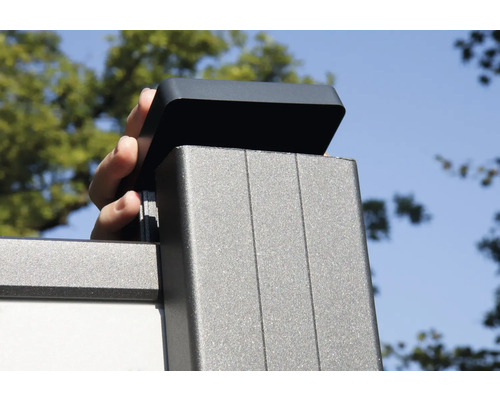 Une main place un couvercle sur un poteau de clôture