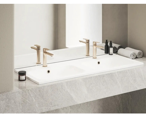 Doppelwaschtisch mit Armaturen, Kosmetikprodukten und Handtüchern in einem Badezimmer.