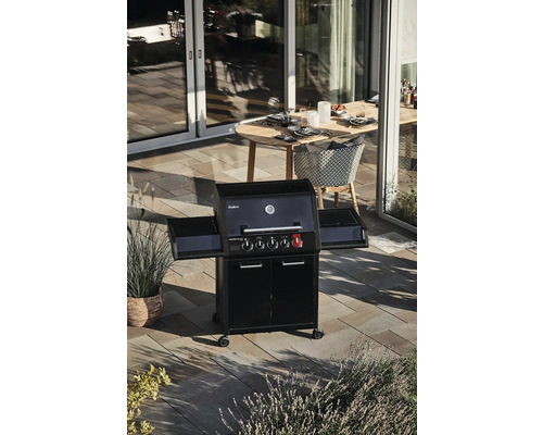 Barbecue à gaz avec tables latérales sur une terrasse avec table à manger