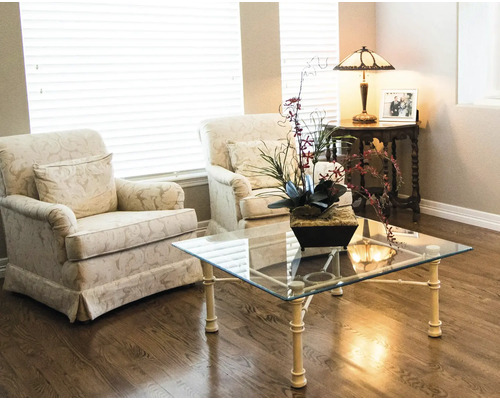 Wohnzimmer mit zwei Sesseln, einem Couchtisch mit Glasplatte und einer Tischlampe