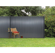 Scène de jardin avec clôture d''intimité, fauteuil et table sur gazon