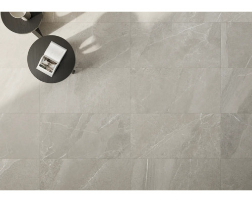 Carreaux de sol clairs aspect marbre posés, avec table et livre.