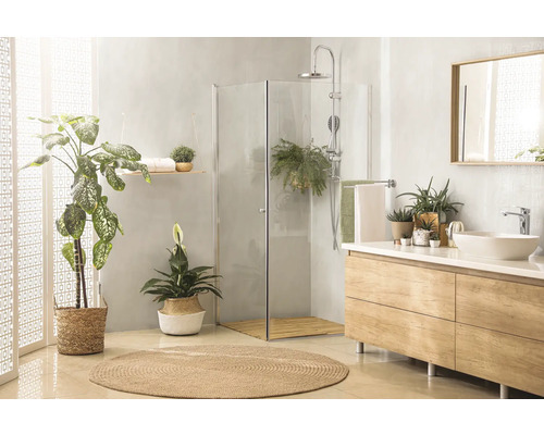 Salle de bain lumineuse avec douche, meuble-lavabo, miroir et plantes pour une ambiance conviviale.