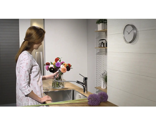 Frau arrangiert Blumen in einer modernen Küche mit Spültischarmatur.