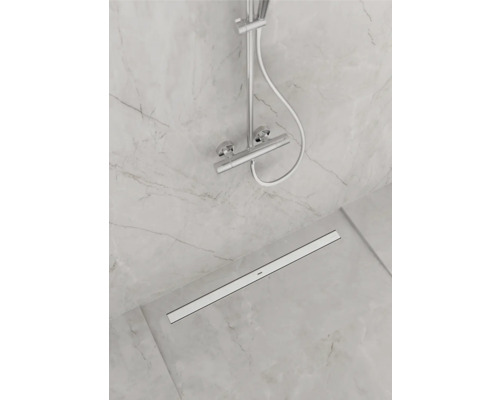 Salle de bain avec robinetterie de douche et caniveau de douche sur sol carrelé