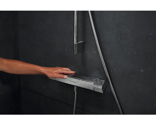 Nahaufnahme einer Hand, die einen Duschthermostat der Marke Hansgrohe bedient.