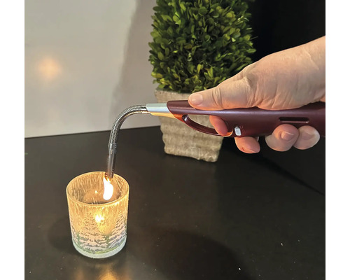 Une main allume une bougie avec un briquet à tige.