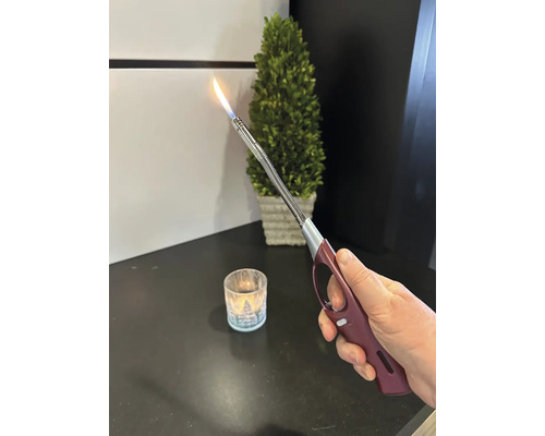 Main tenant un briquet à allonge avec flamme