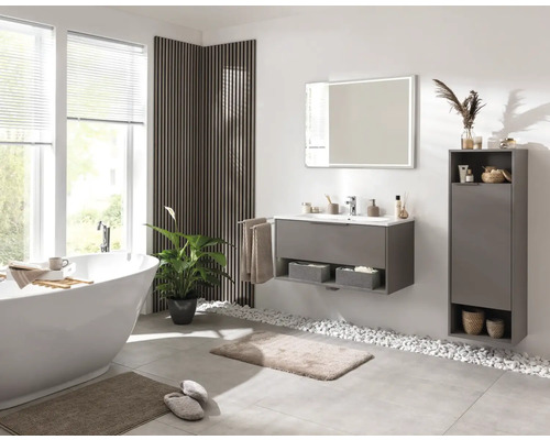 Salle de bains avec baignoire, lavabo, miroir et armoire pour les accessoires de salle de bains.