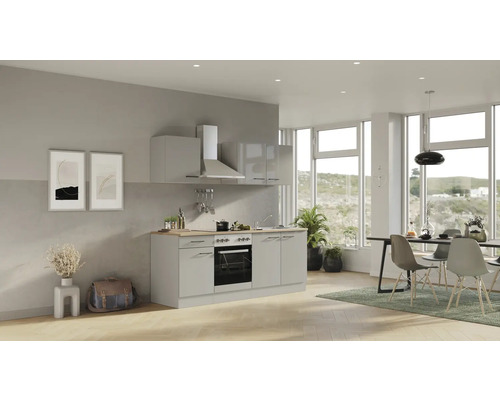 Helle Küche mit Spüle, Herd, Dunstabzugshaube und Esstisch in einem geräumigen Raum mit grossen Fenstern