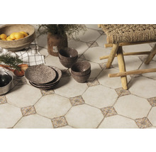 Les carreaux de sol décoratifs avec des accents floraux, combinés à de la vaisselle, des bols et un tabouret en bois, créent une atmosphère de cuisine chaleureuse.