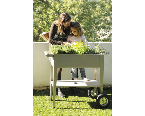 Mutter und Tochter bepflanzen Hochbeet mit Kräutern auf Terrasse