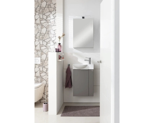 Salle de bains lumineuse avec meuble sous-lavabo, armoire de toilette, WC et revêtement mural décoratif