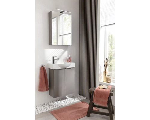 Salle de bains moderne avec meuble sous-lavabo, armoire de toilette, serviettes et tapis de bain.