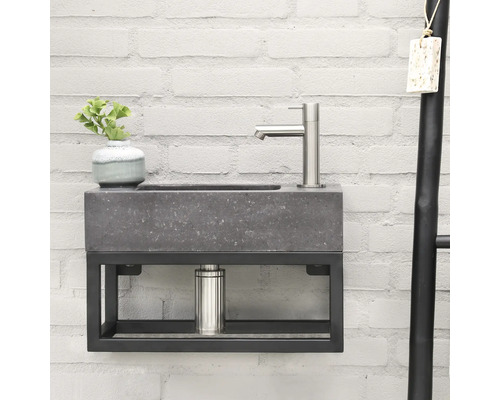 Lavabo moderne avec aspect pierre grise et cadre en métal noir sur un mur de briques blanches