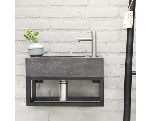 Lavabo avec vasque en béton et structure métallique sur un mur en briques