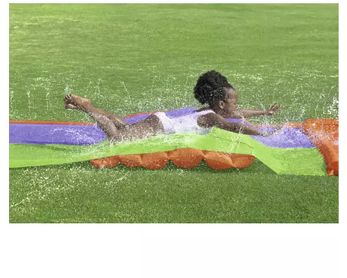 Kind rutscht auf einer Wasserrutsche im Garten