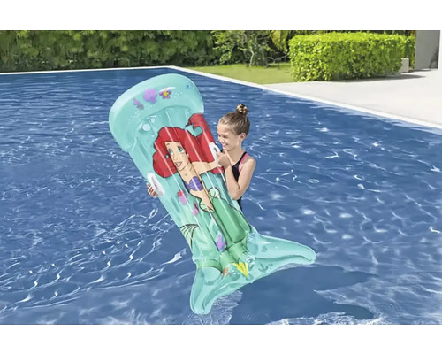 Fille tenant un matelas pneumatique gonflable avec motif Ariel dans la piscine