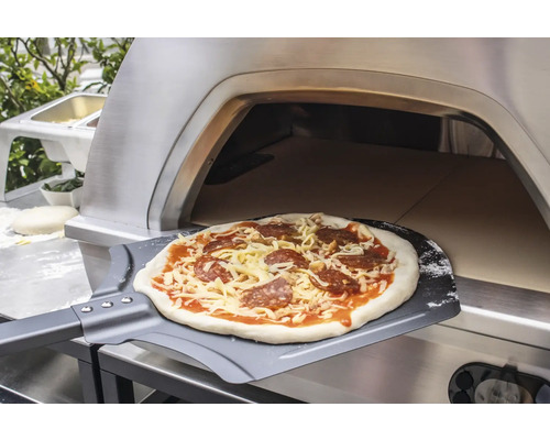 Pizza auf Pizzaschieber vor Pizzaofen