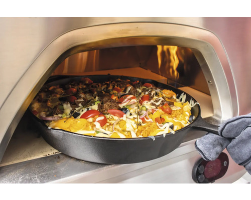 Pizza in einer Gusseisenpfanne wird in einem Pizzaofen gebacken.