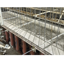 Betonfundament mit Stahlarmierung in einer Baugrube.