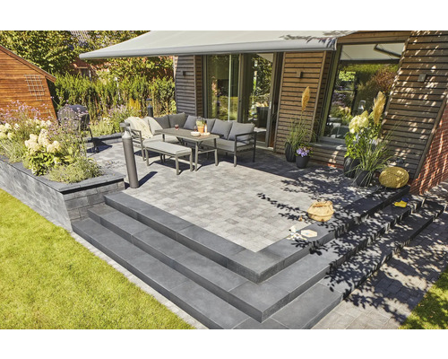 Terrasse avec mobilier de jardin, escalier et plantations dans un aménagement de jardin moderne.