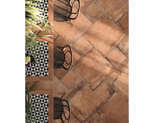 Boden mit Terrakotta Fliesen, Tischen und Stühlen.