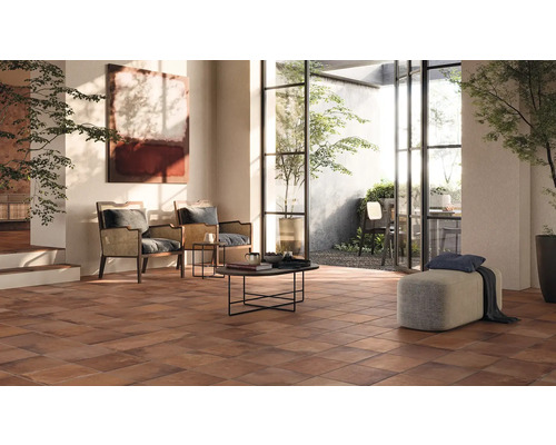 Helles Wohnzimmer mit Terrakottafliesen, Sesseln und Blick in den Garten