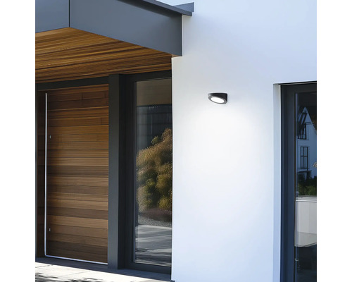 Moderne Hausfassade mit Holzverkleidung, Fenstern und einer Aussenwandleuchte.