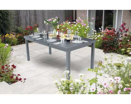 Grauer Gartentisch ausziehbar mit Geschirr und Blumen im Garten