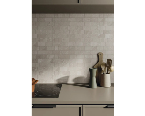 Scène de cuisine avec mur carrelé, plaque de cuisson et ustensiles de cuisine sur le plan de travail.