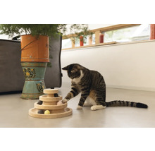 Chat jouant avec un jouet interactif en bois à plusieurs niveaux avec de petites balles.